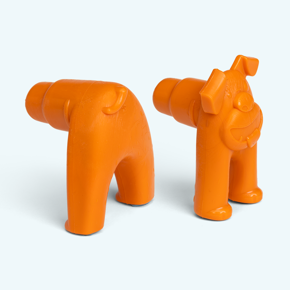 Two orange plastic toys shaped like dogs on a white background