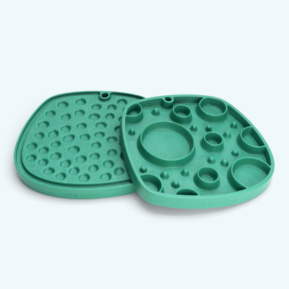 Two green silicone mats with textured surface on a white background