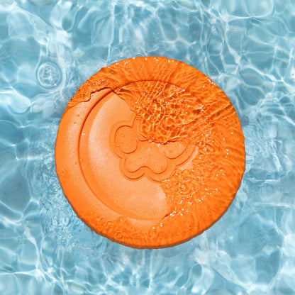 Orange frisbee with a paw print design floating in clear blue water.