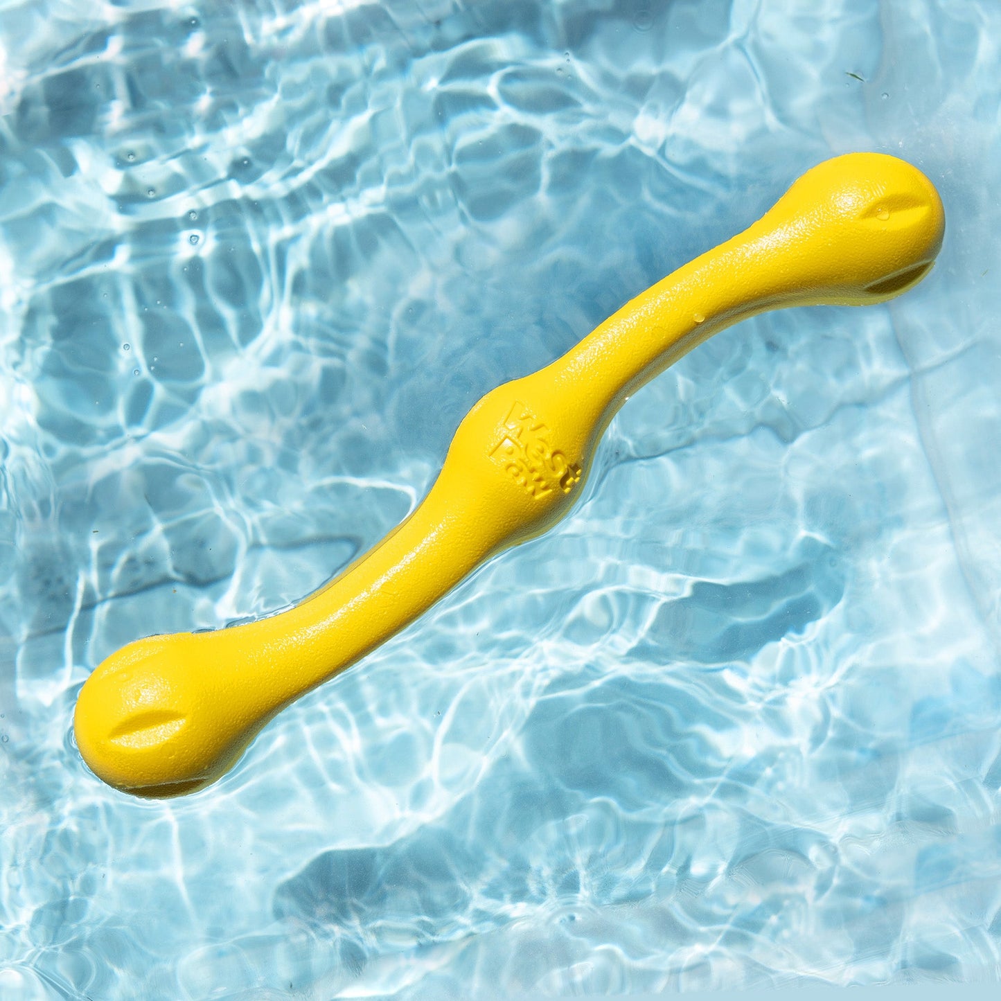 Yellow dog toy floating in clear blue water
