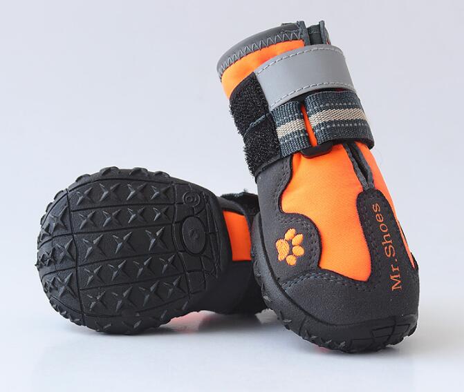 Orange and black dog boots with tread pattern on a light gray background