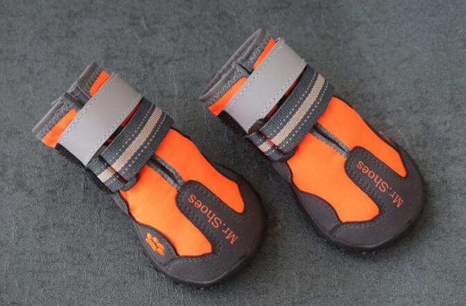 Pair of orange and gray dog shoes on a dark gray background