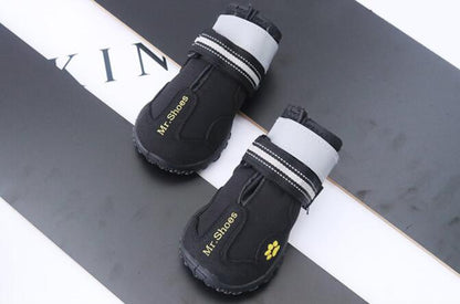 Black dog boots with white soles on a dark surface