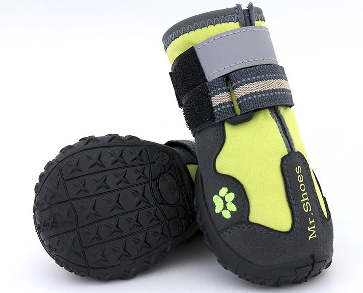 Pair of green and black dog boots with tread sole on a white background
