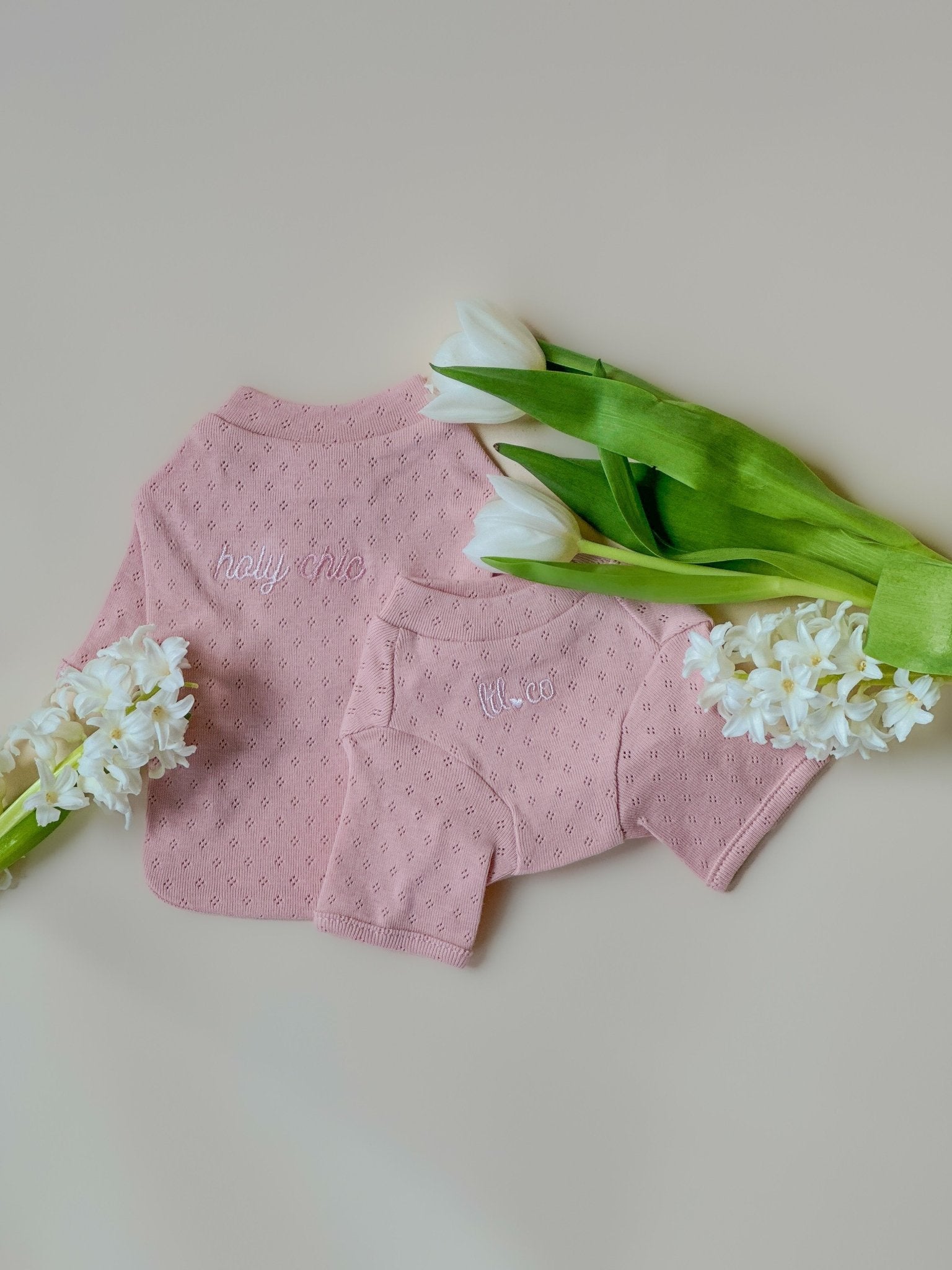 Pink baby outfit with white flowers on a light background