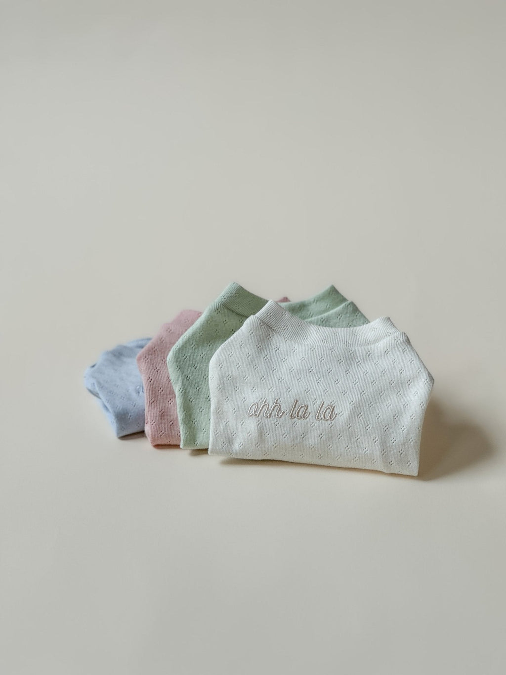 Four folded baby blankets in pastel colors on a light background